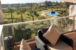 uma varanda com vista para uma piscina e palmeiras em Prestigia Jade Marrakech em Marrakech