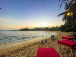 a beach with a red table and chairs and the ocean at Summer lodge-Tangalle in Tangalle