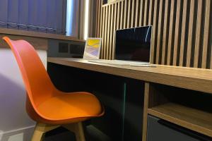 a orange chair sitting at a desk with a laptop at Deluxe 1 Bed Studio 4C near Royal Infirmary & DMU in Leicester