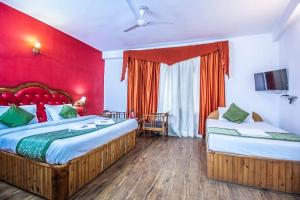 - une chambre avec 2 lits et un mur rouge dans l'établissement Ocean Blue, à Manali