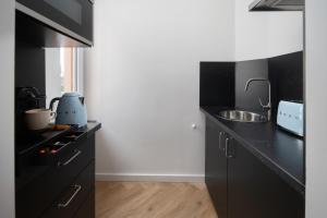 a black kitchen with a sink and a counter at Wohnung 'The Cove' HBF/Messe/ÖVB Arena/City in Bremen