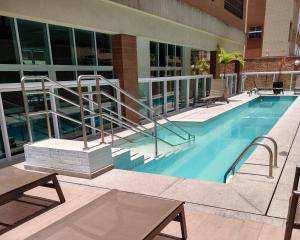 a swimming pool with stairs next to a building at Book Santos - Estanconfor 1201 - Conforto e comodidade na quadra da Praia in Santos