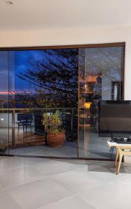 a living room with a large glass wall with a tv at Apartamento pé na areia com vista para o Mar de Itaipu in Niterói