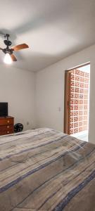 Schlafzimmer mit einem Bett und einem Deckenventilator in der Unterkunft Apartamento pé na areia com vista para o Mar de Itaipu in Niterói