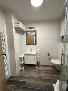 a white bathroom with a sink and a toilet at Apartmány VESNA in Nova Ves nad Nisou