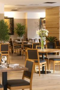 a restaurant with wooden tables and chairs and flowers at Logis Hotel Restaurant SPA Les Oliviers in Loriol-sur-Drôme