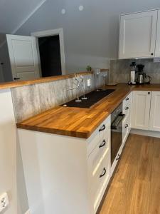 a kitchen with white cabinets and a wooden counter top at Mysig lägenhet på landet. in Ljung