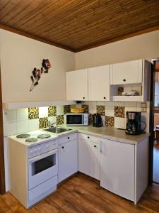 una cucina con elettrodomestici bianchi e armadietti bianchi di Bauernhof Moar a Kernhof