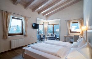 a bedroom with a white bed and a room with chairs at Hotel der Wiesenhof in Pertisau