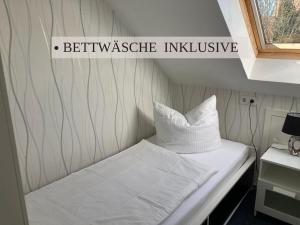 a bed in a small room with a sign on the wall at Krabbe Apartment 10, zentral gelegen neben Muschel-und Krabbenmuseum, bis zu 2 Hunden kostenfrei willkommen in Wremen