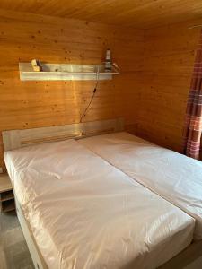 uma cama num quarto com uma parede de madeira em Bungalow WALD & SAND direkt am Strand em Dranske