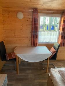 a dining room with a table and a window at Bungalow WALD & SAND direkt am Strand in Dranske