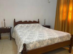 ein Bett in einem Schlafzimmer mit 2 Tischen und einer Tagesdecke in der Unterkunft Casa Pellegrini in Posadas