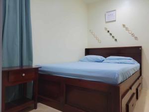 ein Bett mit einem Holzrahmen und blauer Bettwäsche in der Unterkunft New Tropical Inspired Home in Cagayan de Oro
