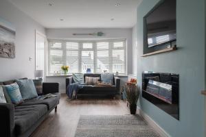 a living room with a couch and a tv at Fully refurbished holiday cottage in Rhosneigr in Rhosneigr