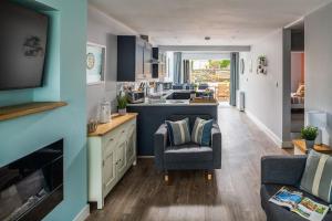 a kitchen with a couch and a chair in a room at Fully refurbished holiday cottage in Rhosneigr in Rhosneigr +30 photos