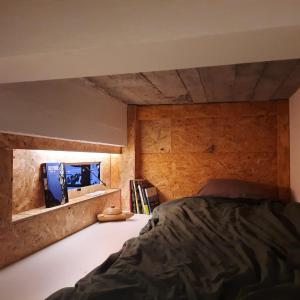 1 dormitorio con 1 cama y pared de madera en Cosy 4p Loft & CoWorking space 5m walk to ski lift, en Briançon