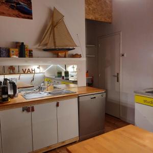 a kitchen with white cabinets and a sink and a boat on the wall at Cosy 4p Loft & CoWorking space 5m walk to ski lift in Briançon