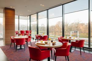 een restaurant met tafels en stoelen en grote ramen bij Babylon Hotel Den Haag in Den Haag