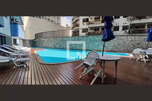 a balcony with a table and chairs next to a swimming pool at Excelente Apartamento no Leblon 02 quadras da praia em prédio com piscina, sauna e academia in Rio de Janeiro