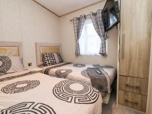 two twin beds in a bedroom with a tv at 13 Harlech Court in Prestatyn