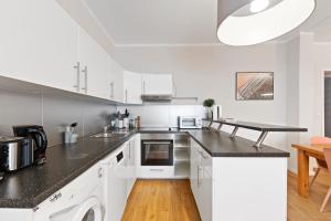 a kitchen with white cabinets and a black counter top at primeflats - Big family apartment Schöneberg in Berlin