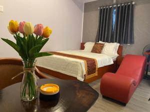 a bedroom with a bed and a vase of flowers on a table at Motel Happy House- Hảo in Bạc Liêu +26 photos