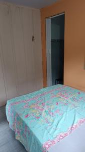 a bed with a blue blanket with flowers on it at Pousada e Camping da Rhaiana - Ilha do Mel - PR in Ilha do Mel