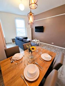 a dining room with a wooden table with plates and wine glasses at Nice and comfy 1 bedroom apartment! in Liverpool