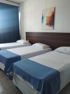 two beds in a hotel room with blue sheets at VILLA DEL SOL Hotel in Fortaleza