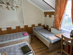 a room with two beds and a table in it at Готель Максим in Drogovyzhe