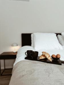 een dienblad met koffiekopjes en croissants op een bed bij Vakantiehuisje Noé in Gorinchem