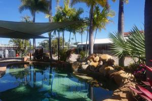 a swimming pool with a fountain and palm trees at Country Ayr Motel in Ayr
