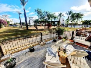 eine Terrasse mit Stühlen, einem Zaun und Palmen in der Unterkunft Bajo Ortosa Valle Golf Resort in Murcia