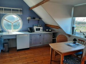 eine Küche mit einem Tisch, einer Spüle und einer Mikrowelle in der Unterkunft Bed en Boterham in Hedel