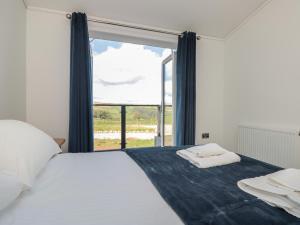 a bedroom with a bed and a large window at Bluebell Lodge in Dartmouth