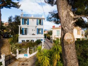 een wit huis met een boom ervoor bij Hotel Albert 1er in Cannes