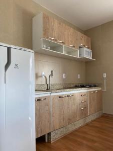 uma cozinha com armários de madeira e um frigorífico branco em Apartamento Inteiro Completo 2 Quartos com AC em Blumenau SC à 10min Vila Germânica em Blumenau