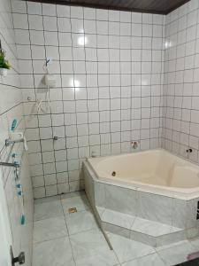 y baño con bañera y azulejos blancos. en Chácara Calixto, en Belém