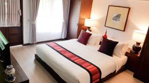 清邁的住宿－清邁蘭特瑞酒店，卧室配有带红色枕头的大型白色床