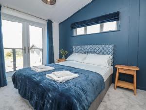 a blue bedroom with a bed with towels on it at Buttercup Lodge in Dartmouth