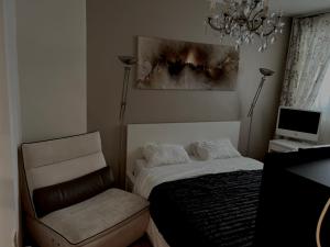 um quarto com uma cama, uma cadeira e um lustre em Chambre Confortable disponible à Genève em Genebra