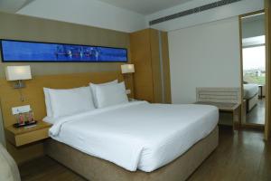 - un grand lit blanc dans une chambre d'hôtel dans l'établissement Sarovar Portico Rivera Ahmedabad, à Ahmedabad