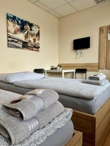 two beds in a room with a tv and towels at Hostel Hodonín in Hodonín