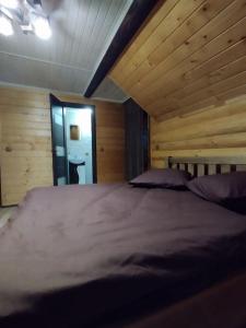un grande letto in una camera con pareti in legno di Садиба у Пасічника a Pilipets