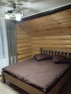 a bed in a room with a wooden wall at Садиба у Пасічника in Pilipets