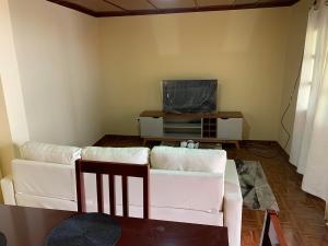 a living room with a white couch and a tv at Ramos Aparttment in São Filipe