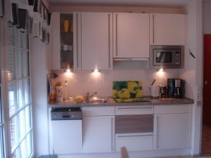 a kitchen with white cabinets and a sink at Sternschnuppe in Sankt Peter-Ording