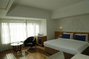 una habitación de hotel con una cama grande y una silla en Sarovar Portico Rivera Ahmedabad, en Ahmedabad