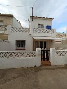 een wit huis met een hek ervoor bij La playa in L'Escala